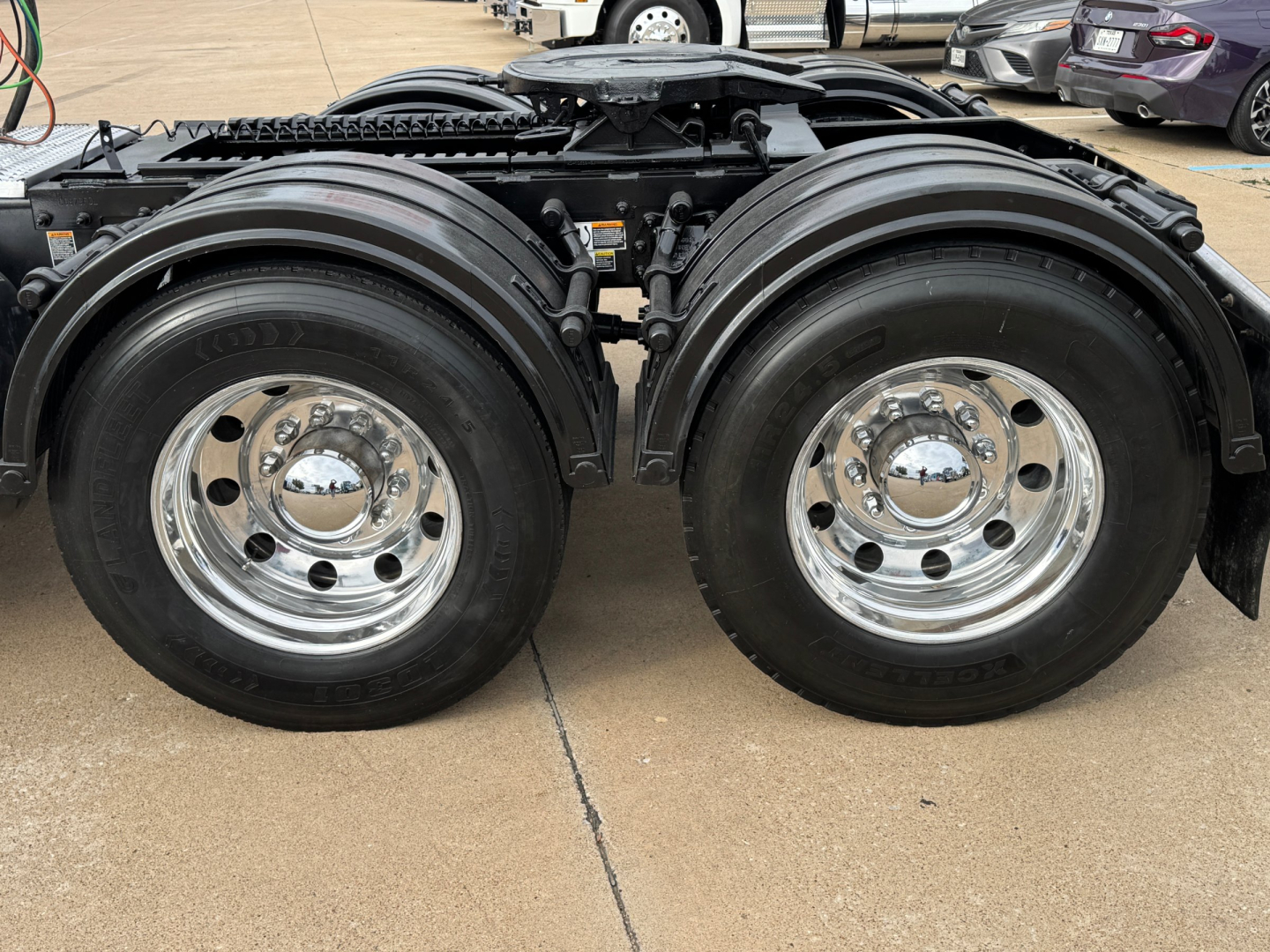 Peterbilt 389 truck rear view showing dual rear axles with polished chrome wheels and black fenders.