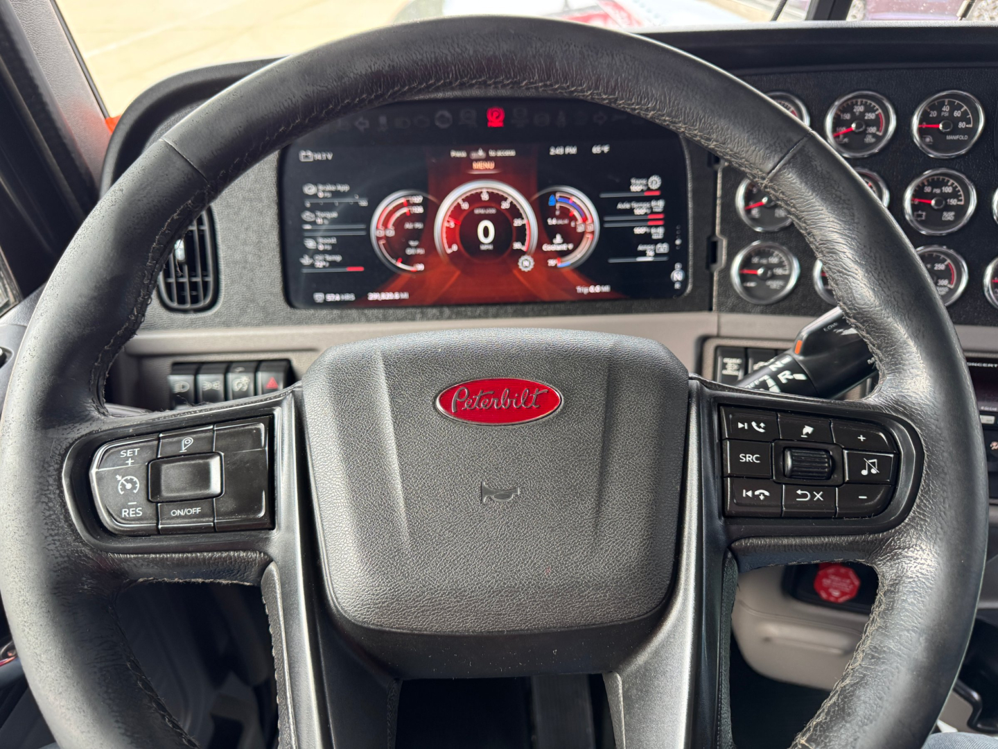 Peterbilt 389 steering wheel and dashboard with digital instrument cluster and controls visible.