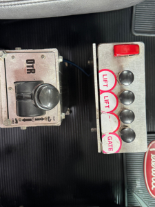 Panel of controls in Peterbilt cab showing a four-button lift/gate control with red top button and labeled lifts and gate, plus an ORR-type unit on left.
