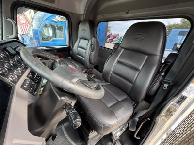 Peterbilt 389 cab interior showing steering wheel, black leather seats, and dashboard with gauges.