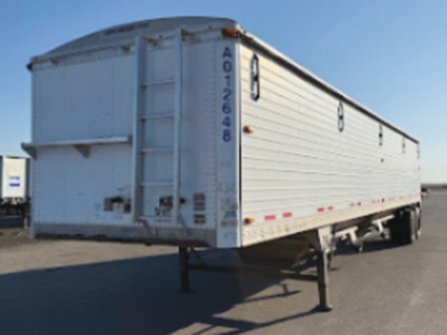 White aluminum Timpte hopper bottom trailer in a side-rear view showing rear doors, ladder, and landing legs; VIN A012648, stock 560360, used trailer.