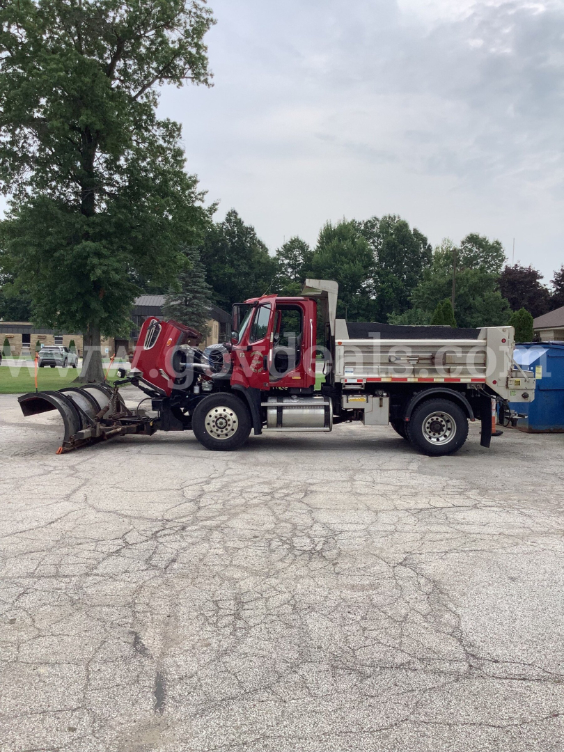 Truck chassis with front cab and dump bed, snowplow attachment at front, Freightliner 108SD dump truck in serviceable condition.
