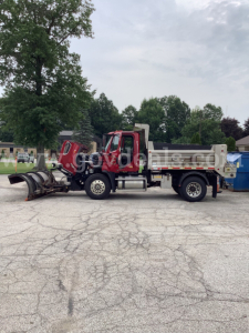 Truck chassis with front cab and dump bed, snowplow attachment at front, Freightliner 108SD dump truck in serviceable condition.