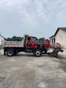 Freightliner 108SD dump truck side view showing front cab and dump bed with plow apparatus attached.