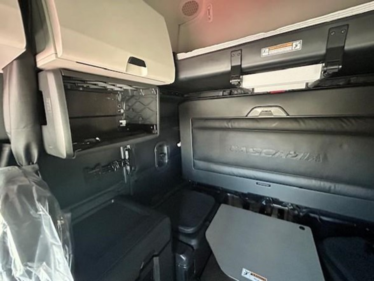 Truck cab interior showing storage compartments and sleeper area with cabinets and control panel.