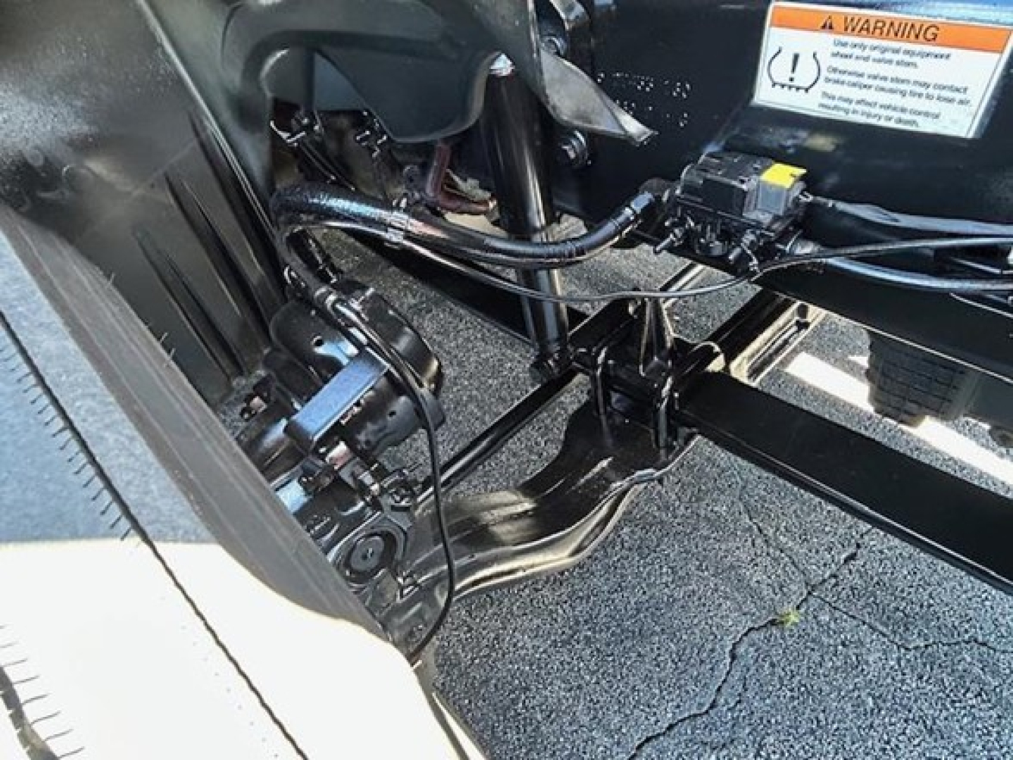 Freightliner Cascadia engine bay area showing cables and label near chassis with warning sticker.