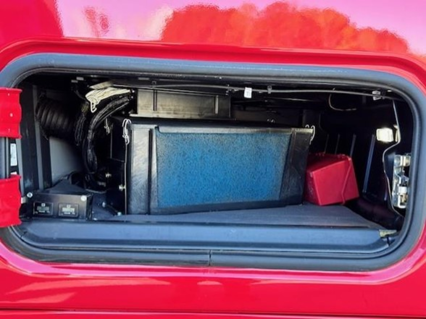 Trunk/hatch of a 2023 Freightliner Cascadia 126 showing a rectangular black battery box and surrounding components in the front storage compartment.