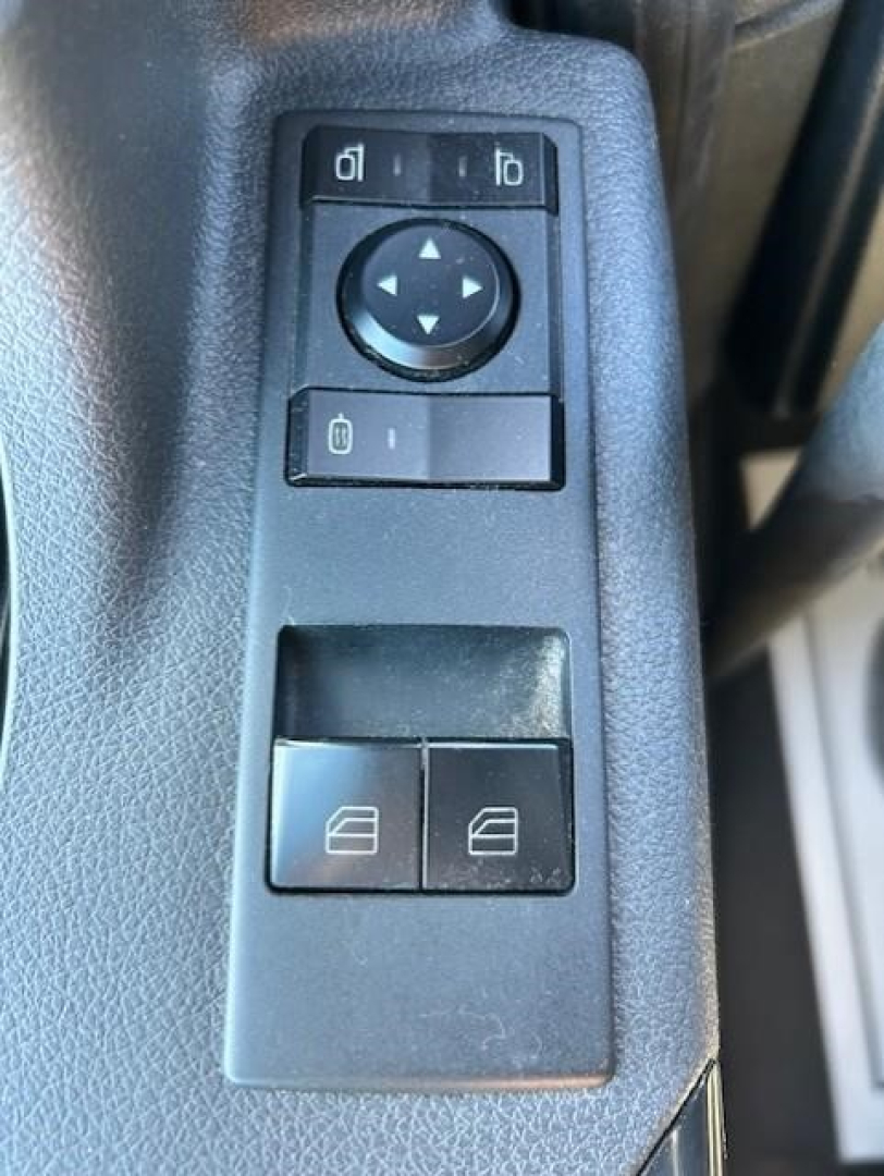 Keypad-style window/door control panel on a Freightliner truck door with arrow pad and two window switches.