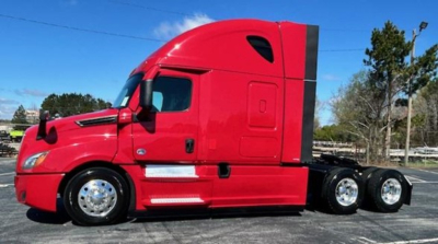 Truck side view of a red 2023 Freightliner Cascadia 126 conventional sleeper tractor showing long wheelbase and tandem rear axles.