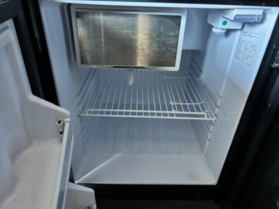 Fridge/freezer unit inside Freightliner Cascadia cab showing empty small freezer area with door open.