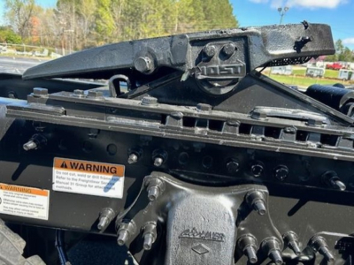 Freightliner Cascadia engine bay area showing hitch components and warning labels on chassis.