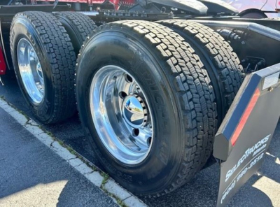 Freightliner Cascadia 126 wheel and dual rear axle tires close-up showing polished rims and tread pattern.