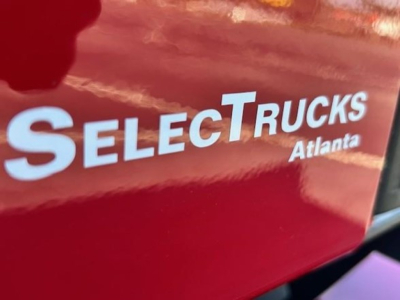 SelectTrucks Atlanta logo on red surface with partial reflection.