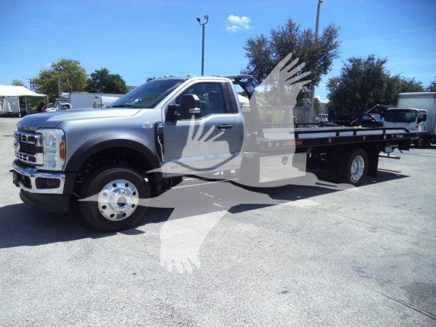 Ford F-600 XP?ton flatbed tow truck in a light gray color, side view showing rollback bed and dual rear wheels.