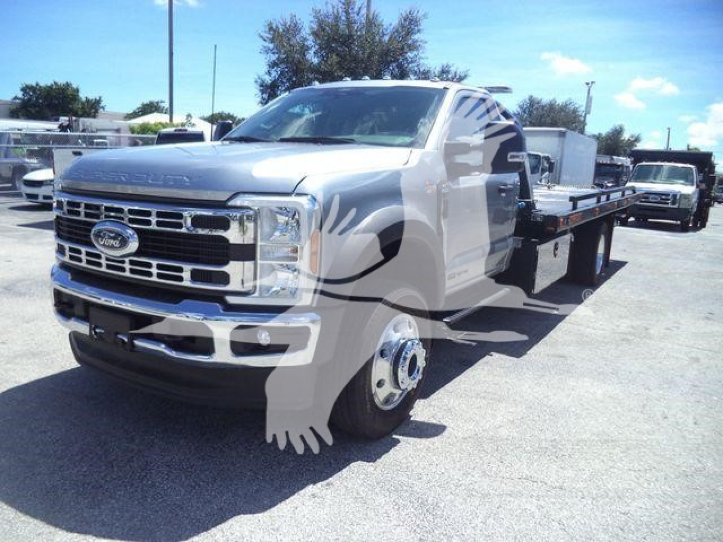 Ford F-Series truck with flatbed tow body, front grille and headlights visible, metal wheels, cab and long chassis in a dealership lot.
