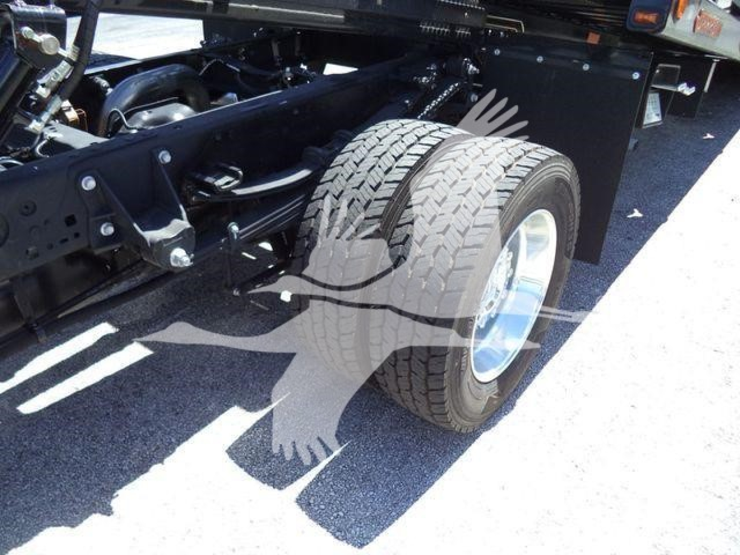 Truck rear wheel assembly and suspension viewed from side showing dual rear tires and chassis components.