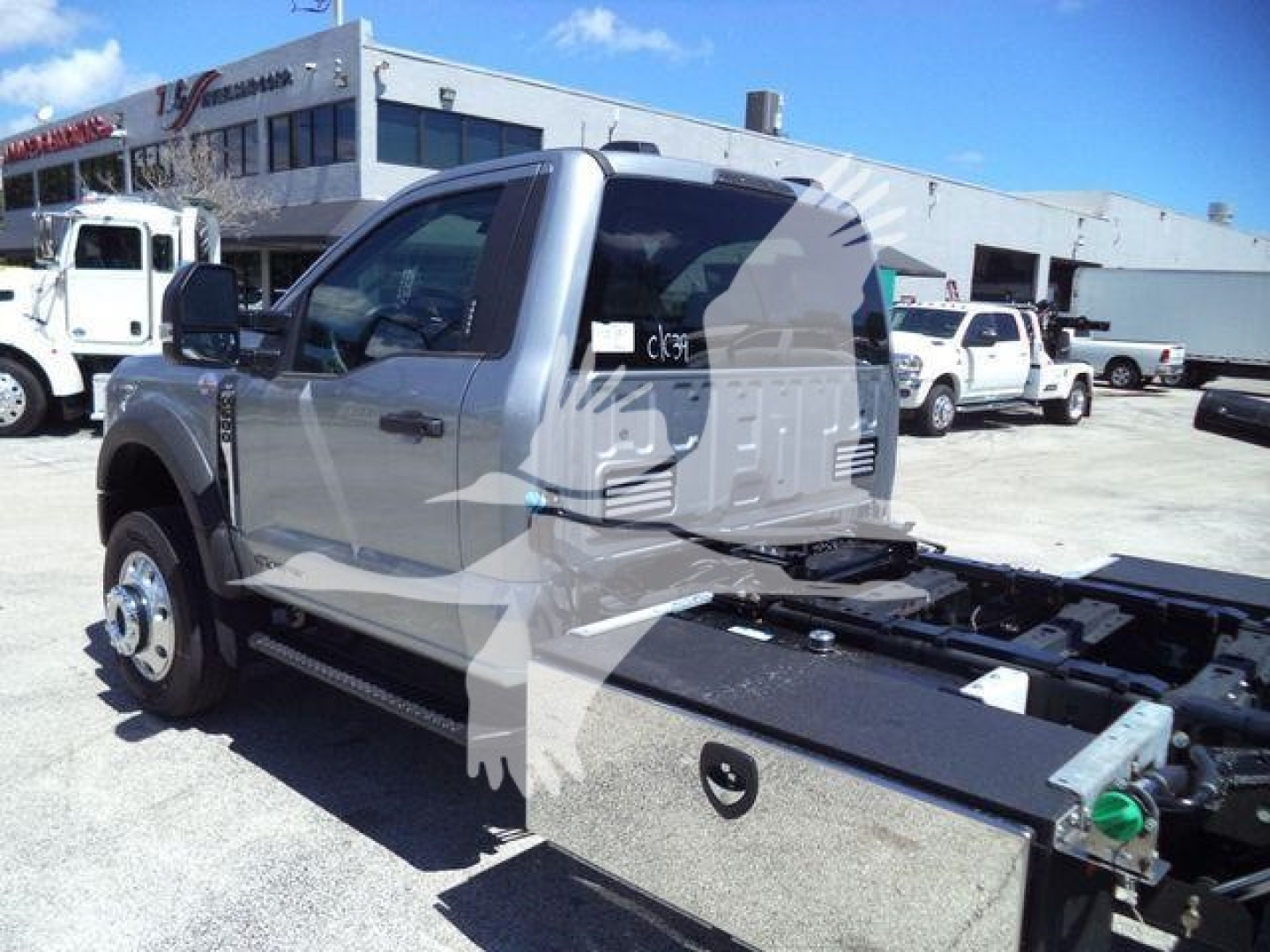 Ford F-600 pickup truck cab and chassis with flatbed rollback bed visible in a dealership lot.