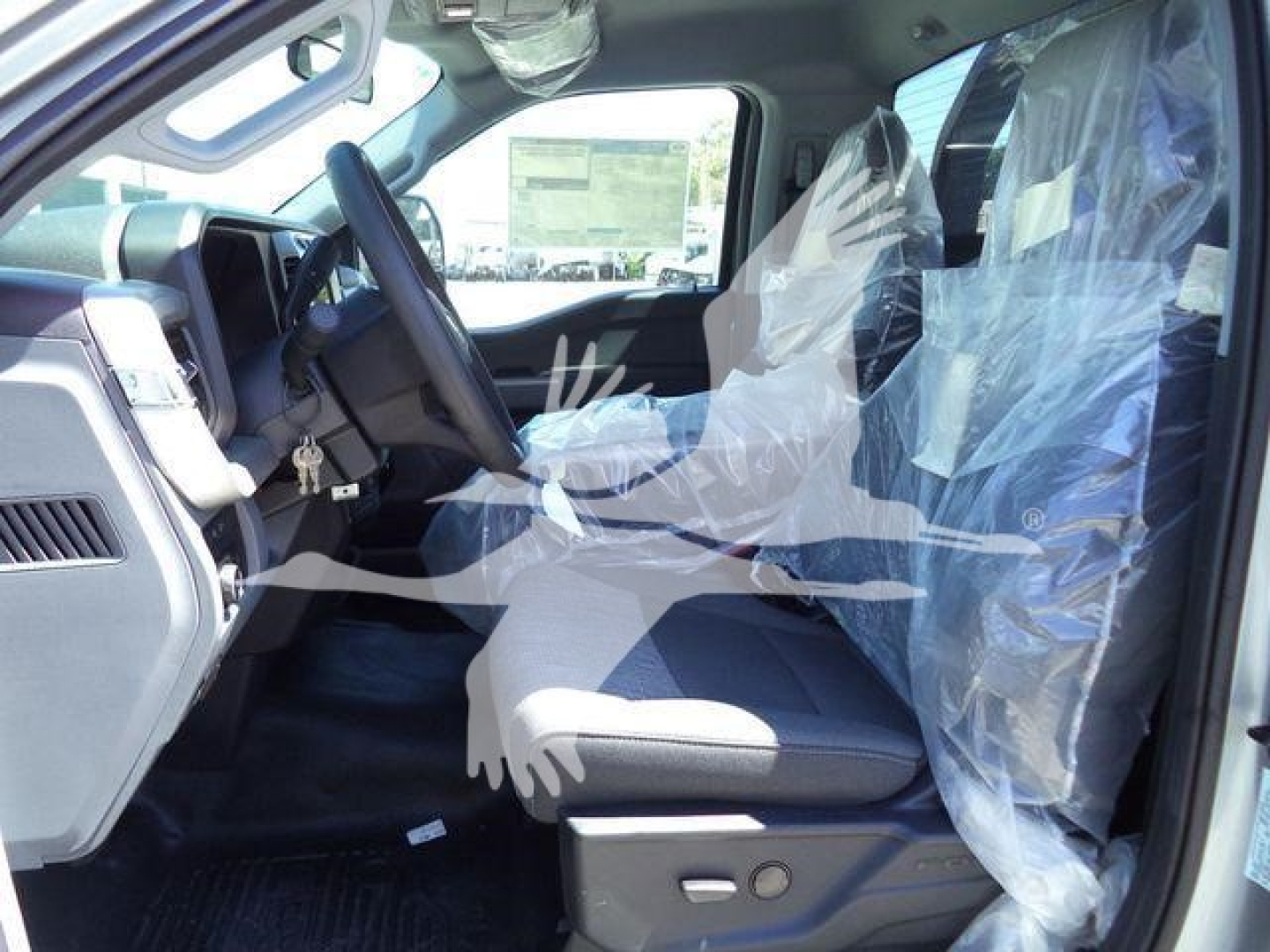 Truck interior showing front seats wrapped in plastic and steering wheel in view.