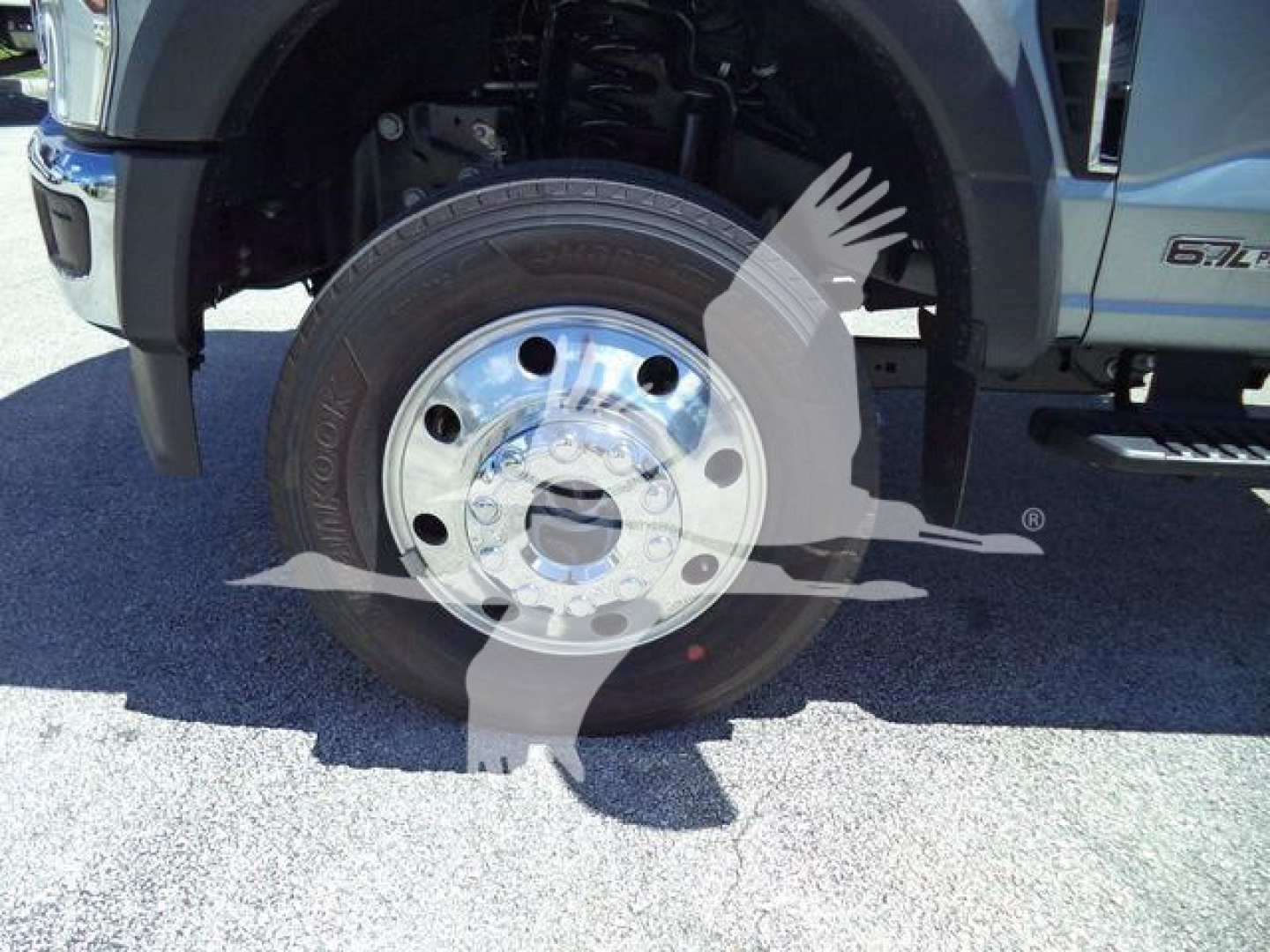 Truck front wheel close-up showing chrome hub and tire on Ford F-600 XLT rollback chassis.