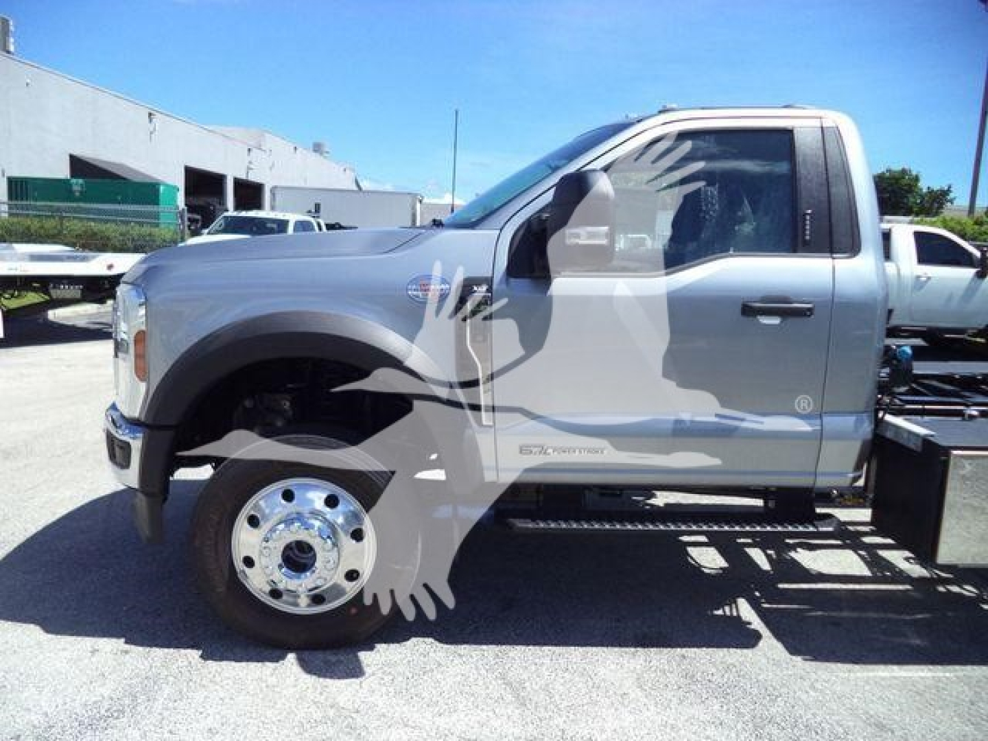 Ford F-600 rollback tow truck side view showing front wheel, cab with XL badge and step, metallic silver color.