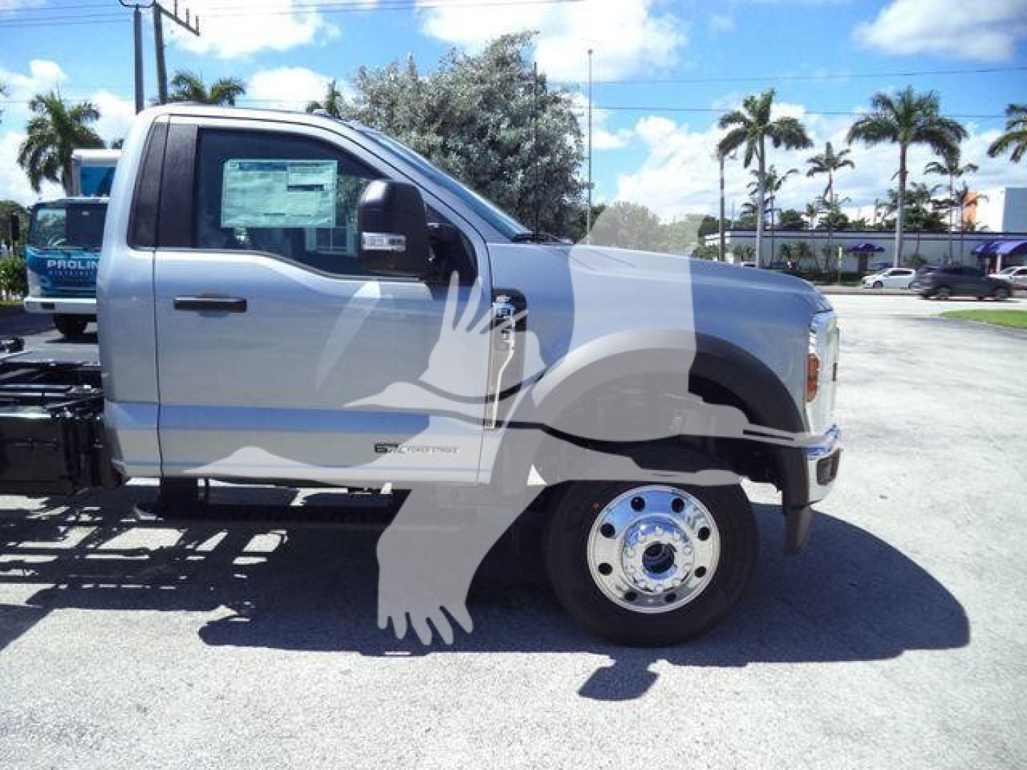 Truck side view showing front half of a 2024 Ford F-600 XLT roll-back truck with driver door, front wheel, and dealership sticker on the window.