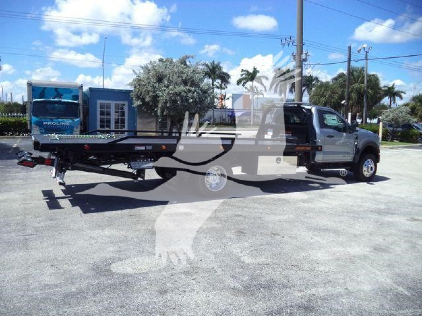 Truck with rollback bed and tow winch in a parking lot, 2024 Ford F600 XLT front cab side view.