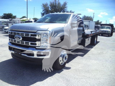 Ford F-Series truck with flatbed tow body, front grille and headlights visible, metal wheels, cab and long chassis in a dealership lot.