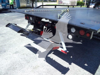Rear view of a flatbed rollback tow truck with hydraulic ramps and taillights visible.