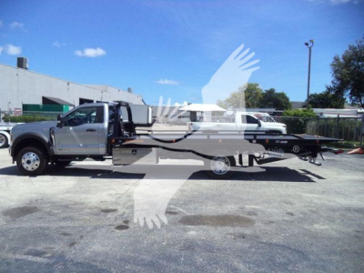Truck in a parking lot showing a 2024 Ford F600 XLT rollback tow truck with extended flatbed and tow setup visible.