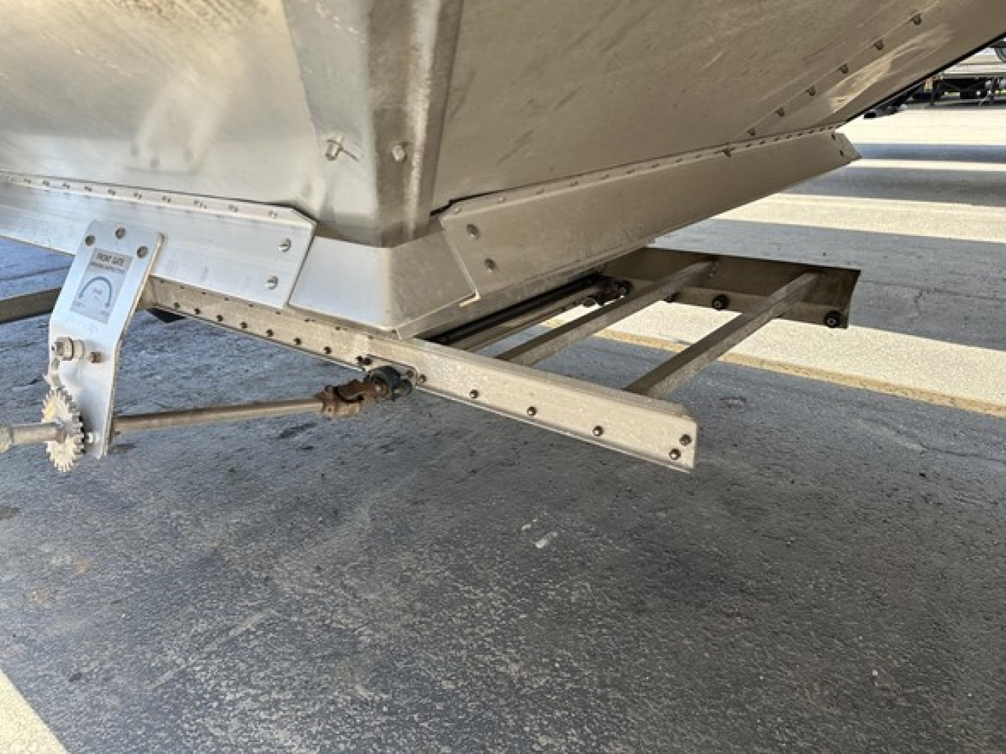 Trailer underside showing hopper hitch assembly and mounting bracket with bolts.