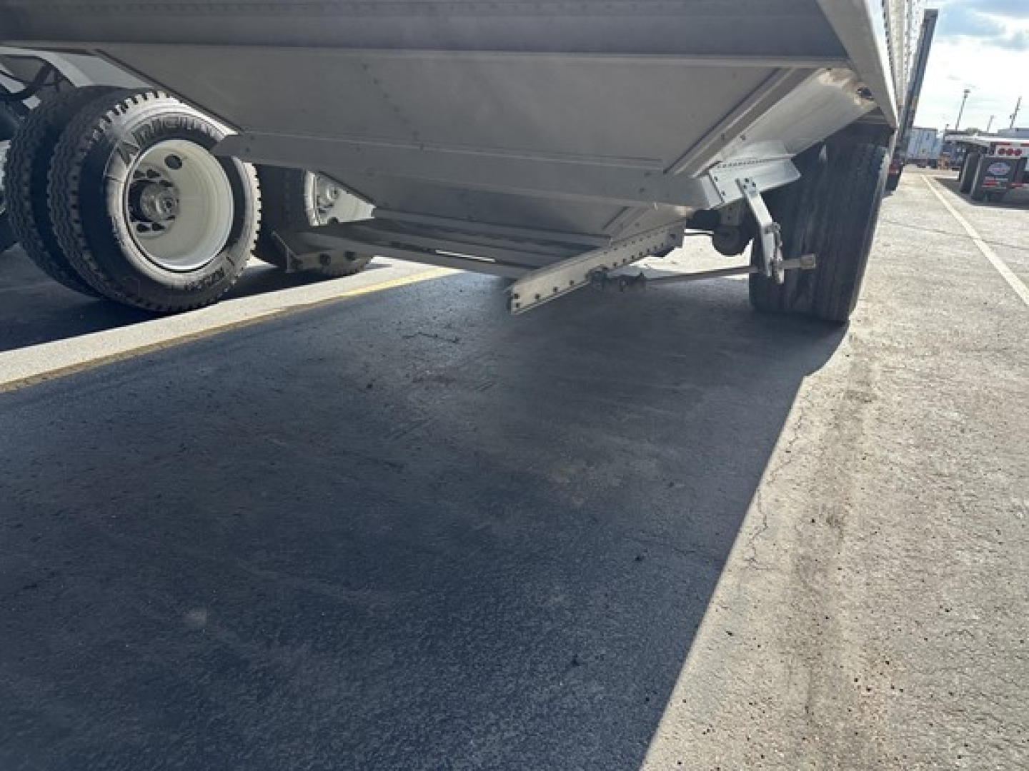 Trailer underside view of a grain hopper trailer showing support framework and landing gear in a buyer lot.