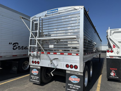 Stoughton grain hopper trailer rear view showing metal slat sides, rear doors, lights, and mud flaps with Utility brand stickers.