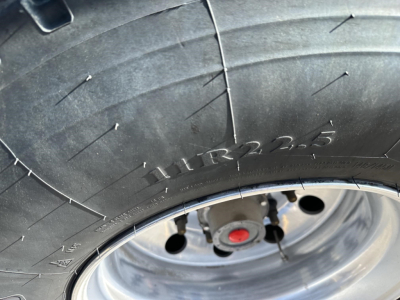 Trailer tire close-up showing tread with markings and wheel hub; part of a Stoughton hopper trailer.