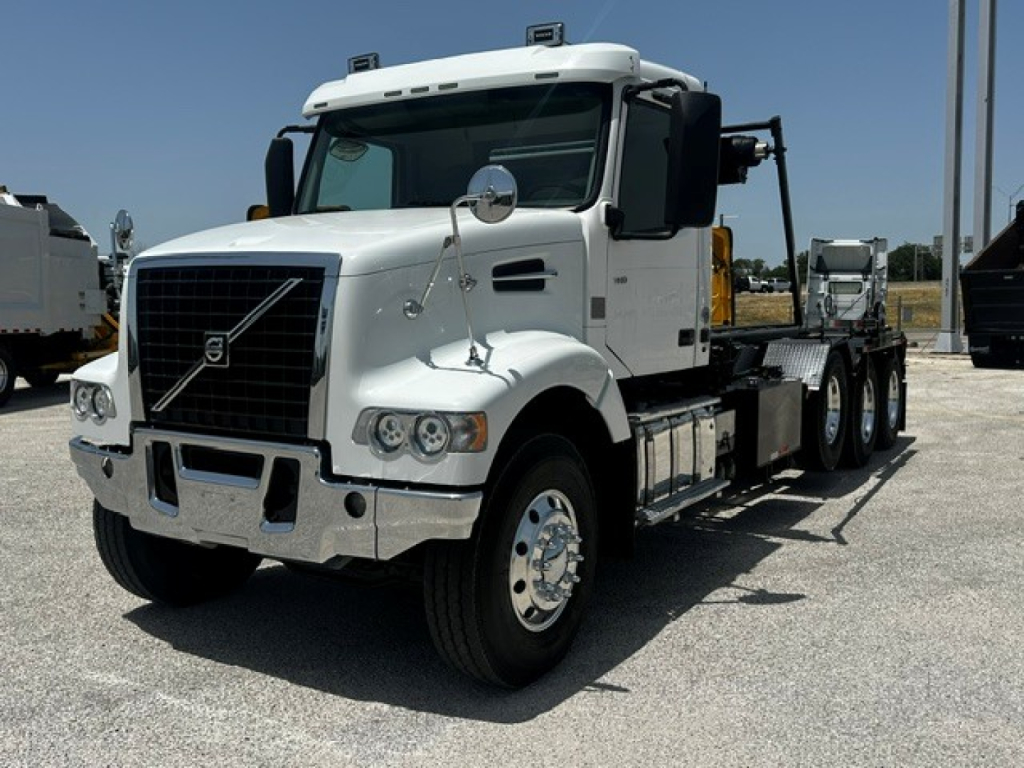 Volvo VHD rolloff truck in white showing front grille and wheel, side view with chassis and flatbed.