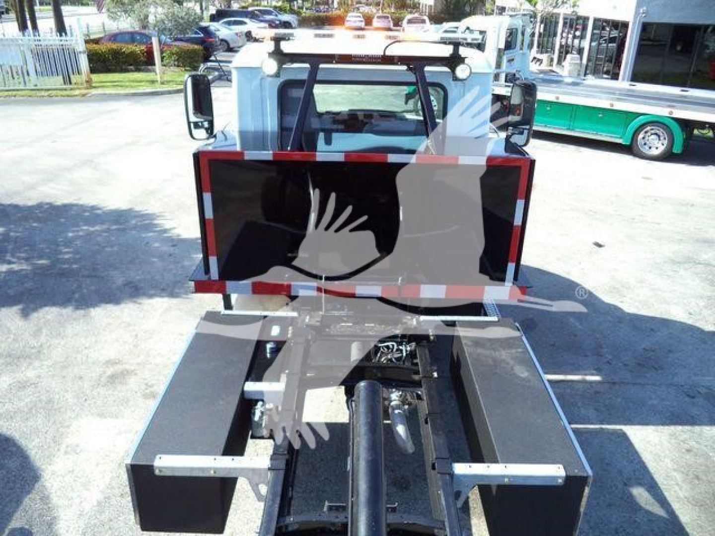 Front view of a 2026 Mack MD6 rollback truck showing a metal bed and towing equipment, with a black hydraulic arm and rear mounting hardware visible.
