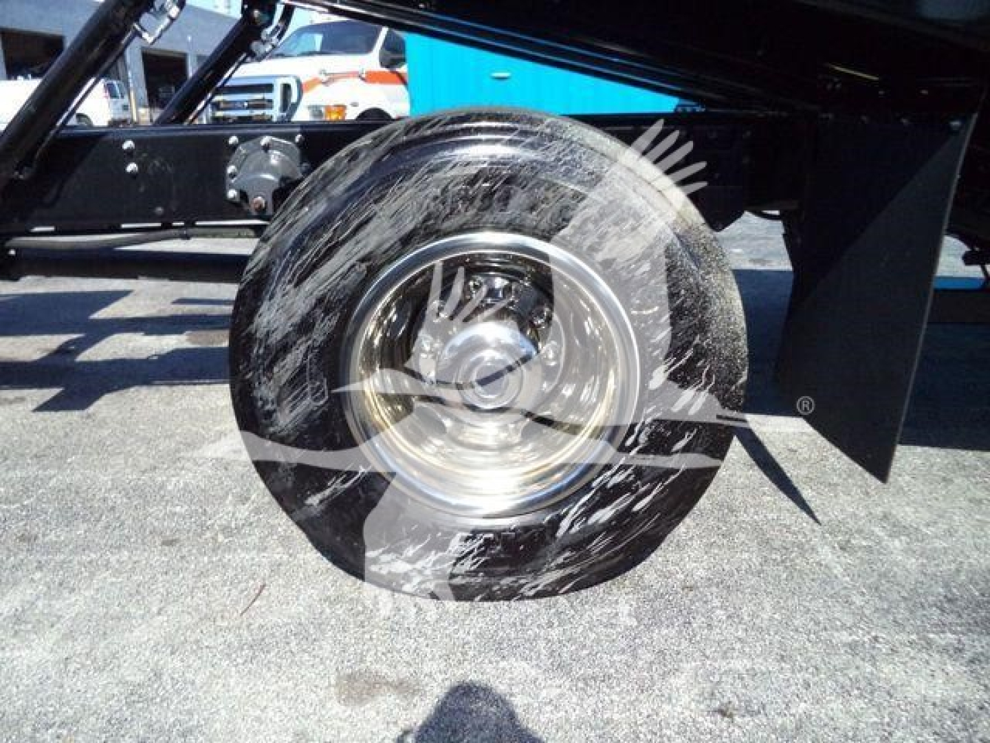 MD6 truck wheel and a portion of the undercarriage showing a smooth metal wheel hub and black frame, gravel surface in background.