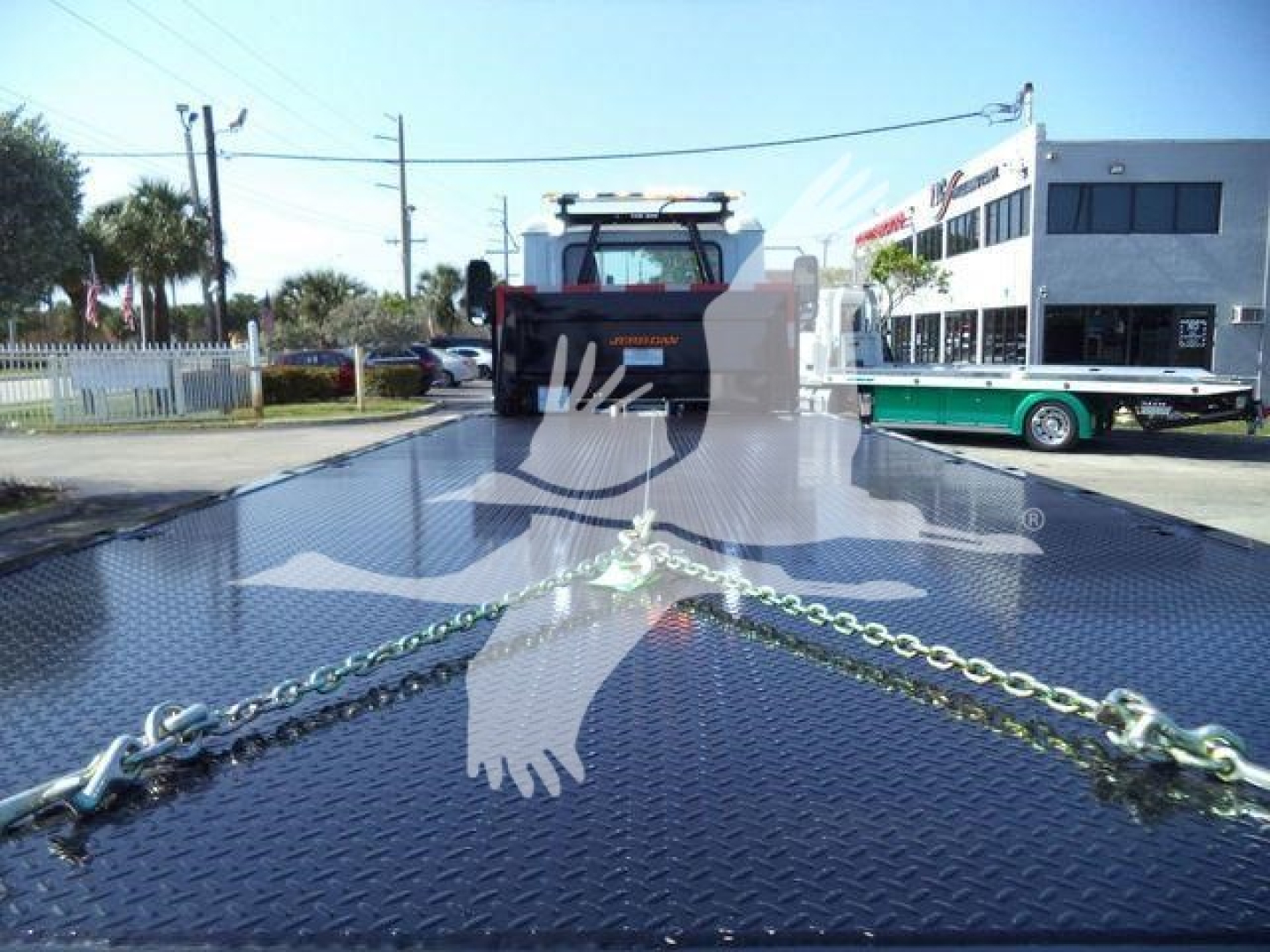 MD6 truck rollback bed with chains on diamond plate and front cab in background