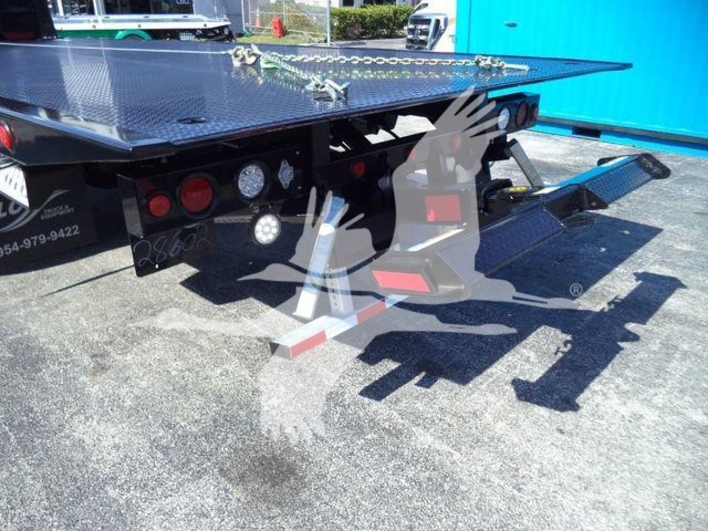 MD6 flatbed tow truck in-view with rear deck and gooseneck hitch, lights, and taillights; showcases metal Diamond plate surface and hydraulic components.
