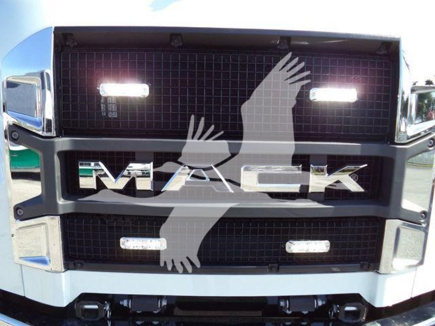 Mack MD6 grille close-up showing illuminated grille lights and large 'MACK' logo across center.