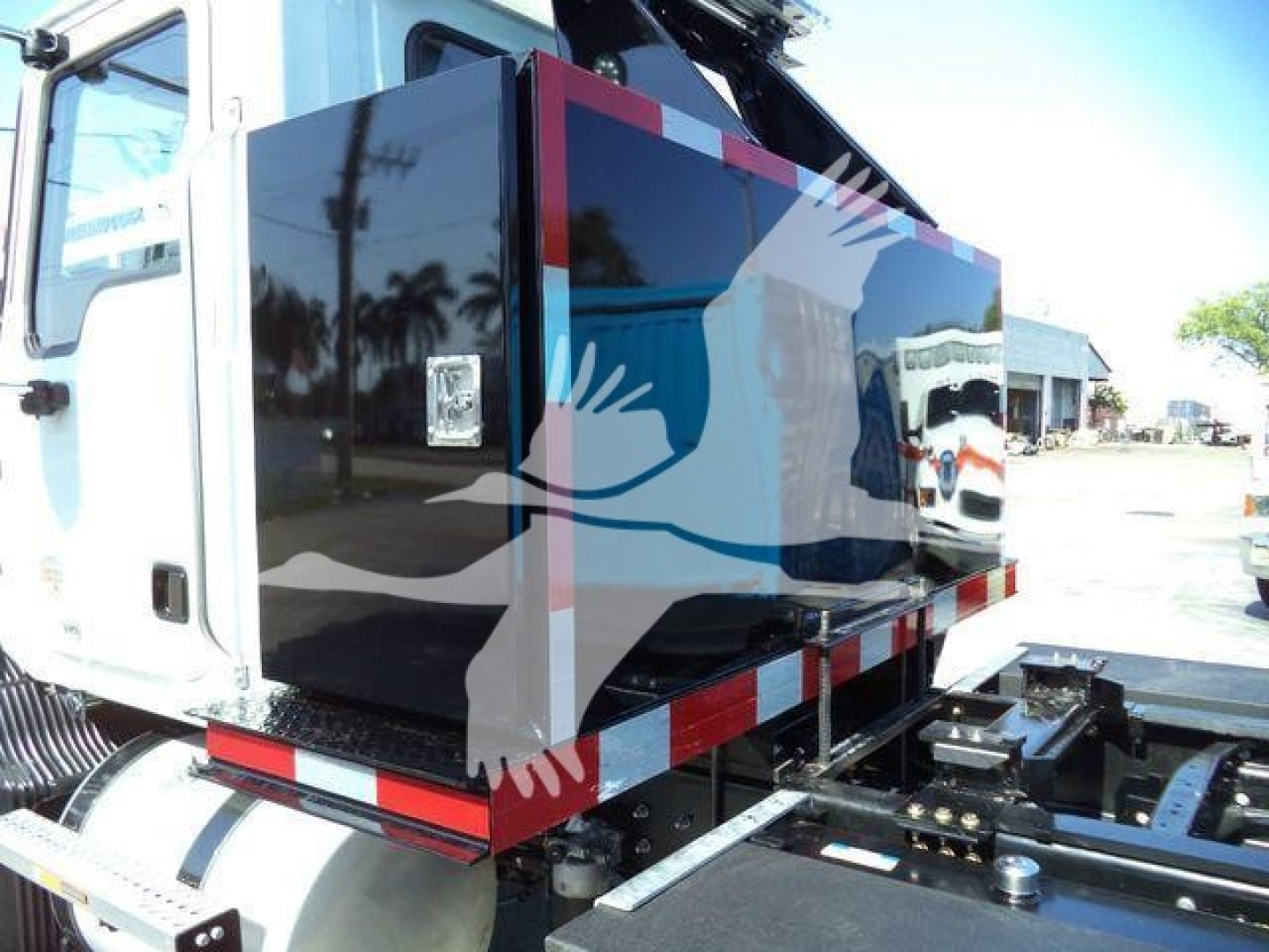 MD6 Mack rollback truck body side view showing black panel with graphic design and reflective red/white stripes under cargo area.