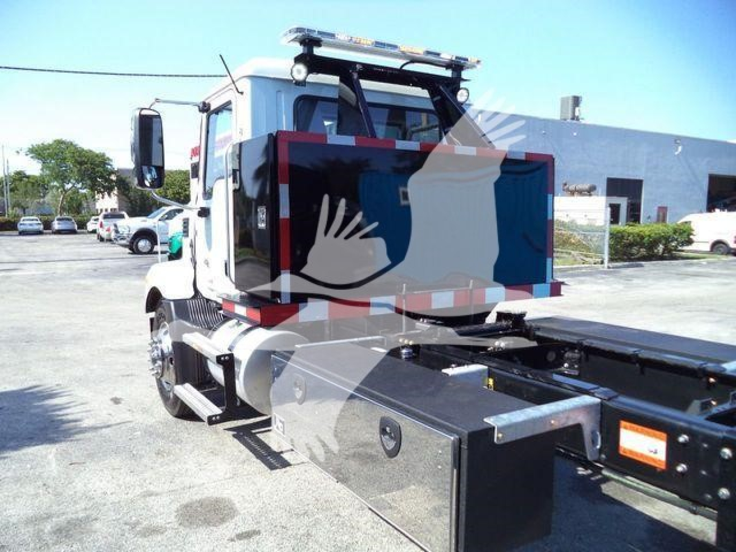 MD6-series Mack rollback truck cab with tool/storage box on side and flatbed chassis, rear view showing cab mirrors and equipment mounting