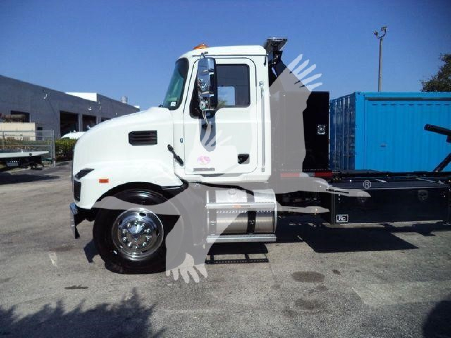 2016 Mack Md6 rollback truck cab side view showing white cab and black chassis with blue container in bed.