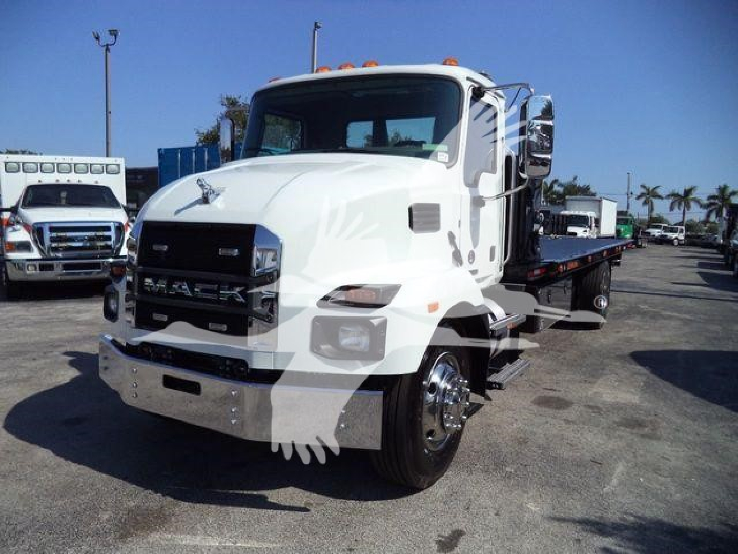 MD6 Mack rollback truck in a dealership lot; visible text includes MACK on the grille, MD6 is not clearly visible; side shows white cab with orange roof lights; background includes other trucks.