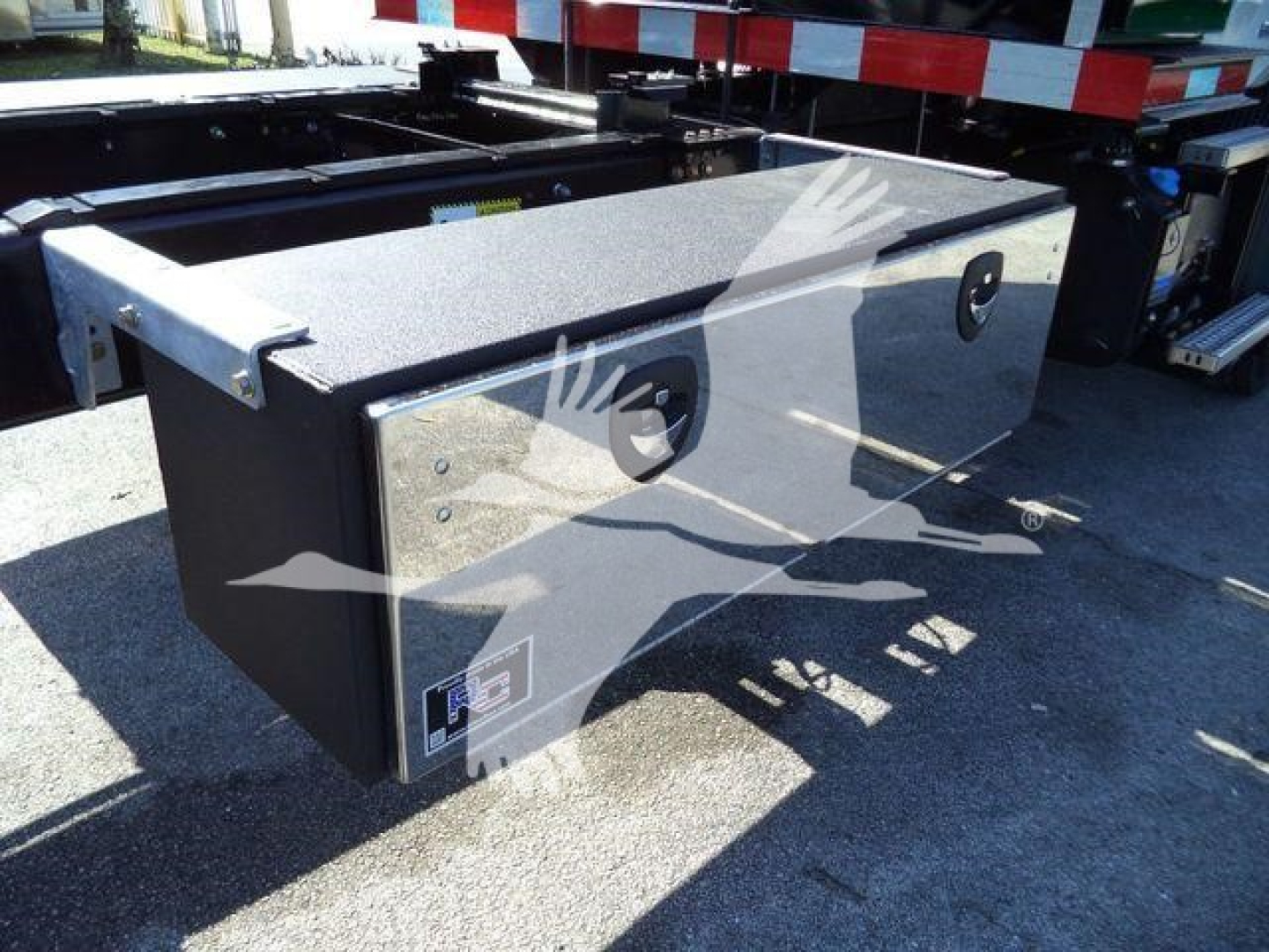MD6 tunnel toolbox mounted on back of Mack MD6 rollback truck showing heavy-duty metal storage box with two circular recessed handles and a sticker at lower corner.