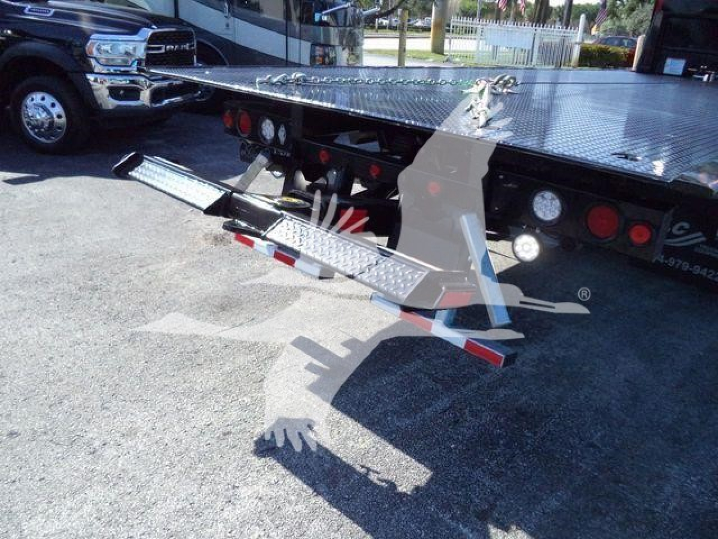 MD6 rollback truck showing a fold-out aluminum loading ramp and rear platform attached to flatbed; metal steps extend downward.