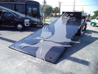 MD6 flatbed tow truck with a lowered ramp and starburst graphic on the deck viewed from the rear-right side.