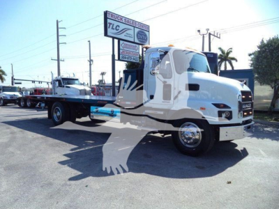 2026 Mack MD6 roll-back truck with flatbed view showing cab and chassis, dealership signage in background.