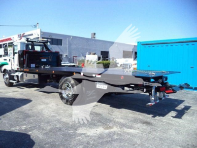 MD6 rollback truck chassis in a lot showing flatbed with hydraulic system and wheels visible