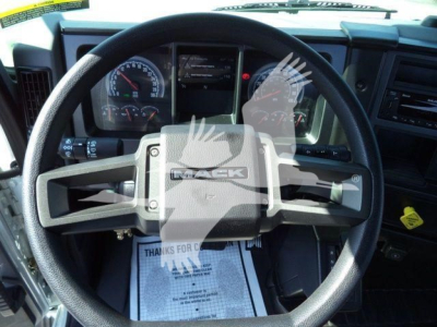 Mack MD6 dashboard and steering wheel in new truck displaying instrument cluster and steering wheel badge, cab interior details visible.