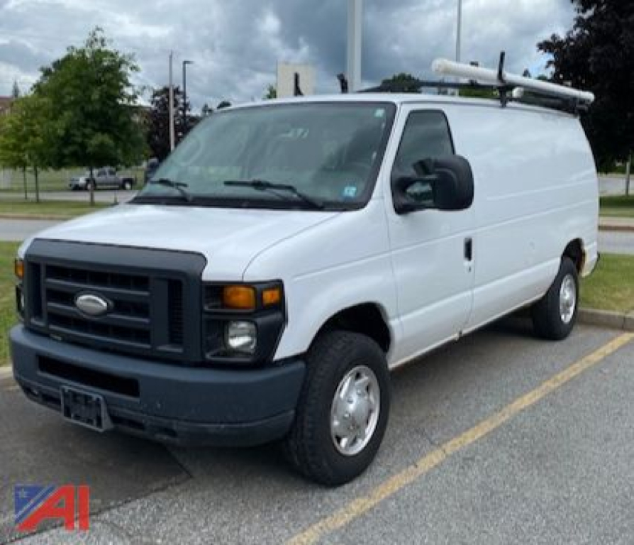 Ford E350 cargo van showing front grille, headlights, black bumper, white body, and roof-mounted ladder rack.